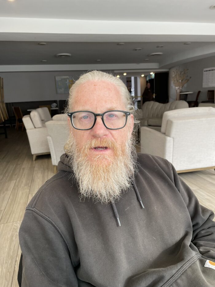 man in gray hoodie with white hair and beard