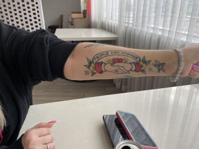 woman shows a tattoo on her arm that says People Can Change