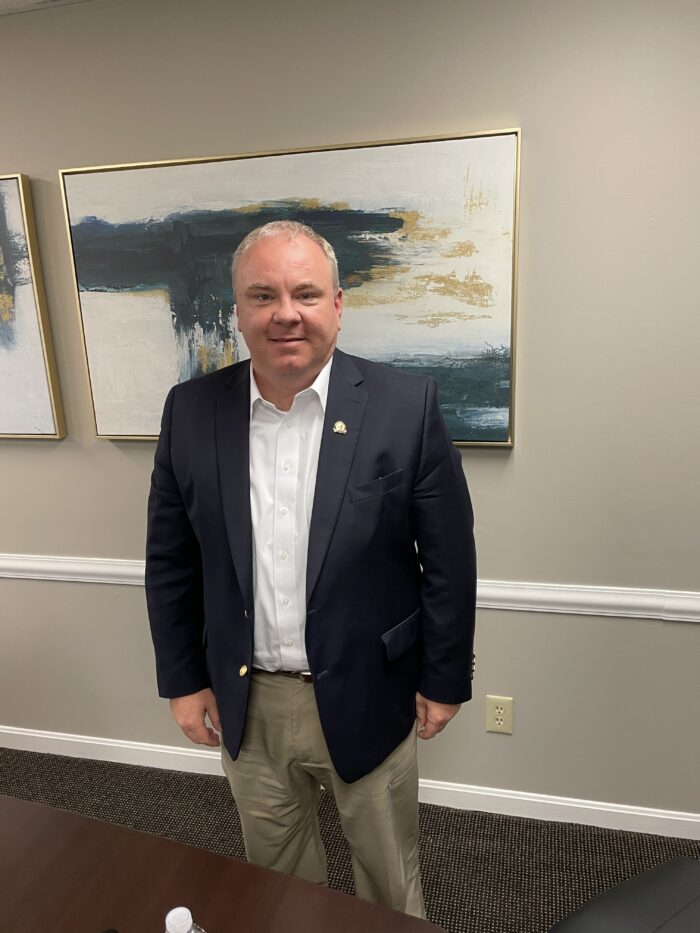 Man in black sport coat and tan slacks looks at camera