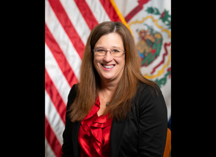 Woman in black and red in front of WV and US flags