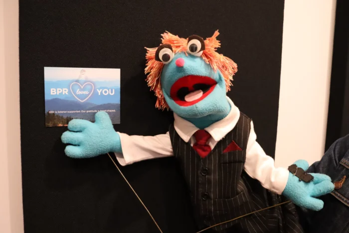 A blue puppet with orange hair.