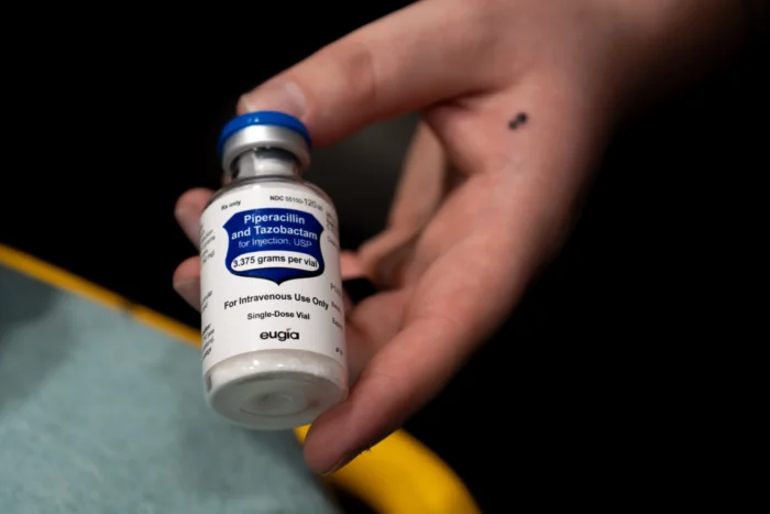 A photo of someone's hand holding a vial of antibiotics. 