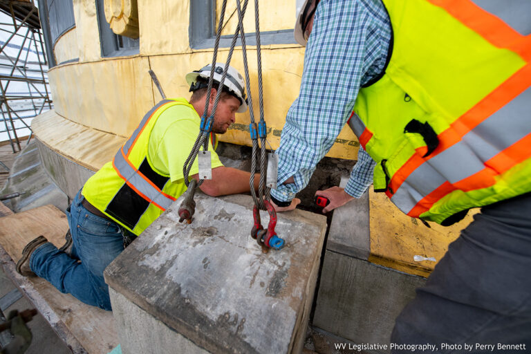 Two construction workers perform repairs inside a building.