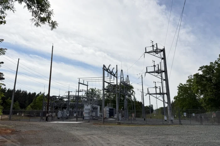 A landscape photo of an electric substation. there are electrical lines coming out of a silver structure. It is outside. 