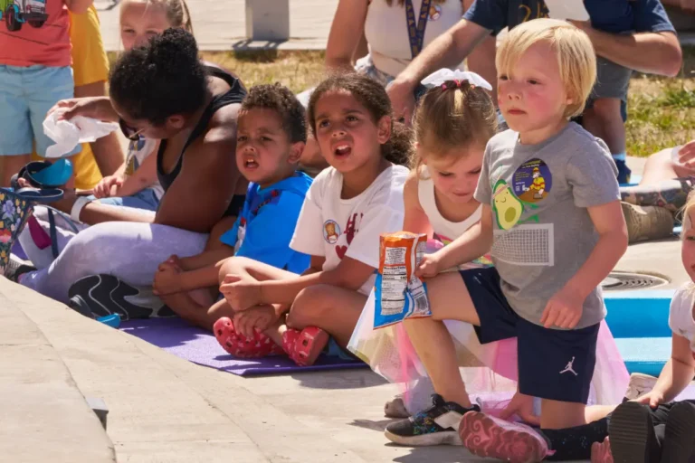 Four children sit on yoga mats and look toward a speaker.