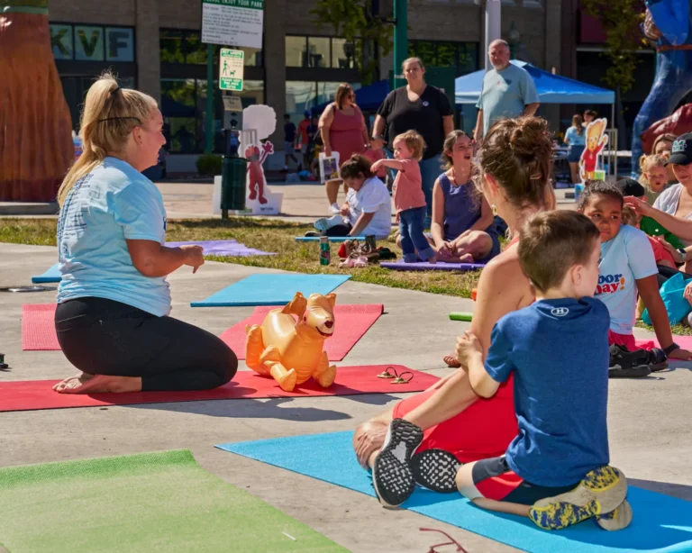 Several people are shown doing yoga outside on a sunny day.