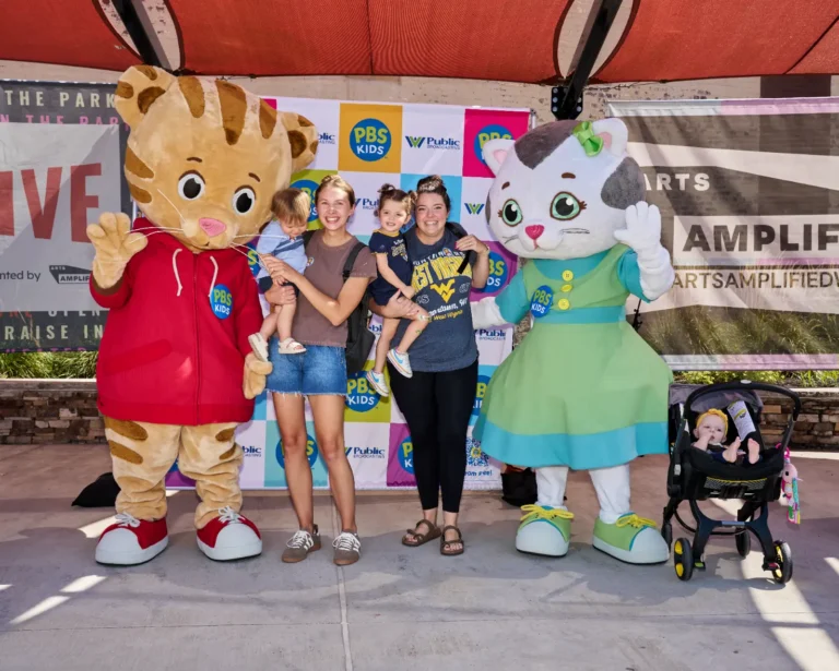 Four people, two adults and two children, pose for photos with Daniel Tiger and Katerina Kittycat.