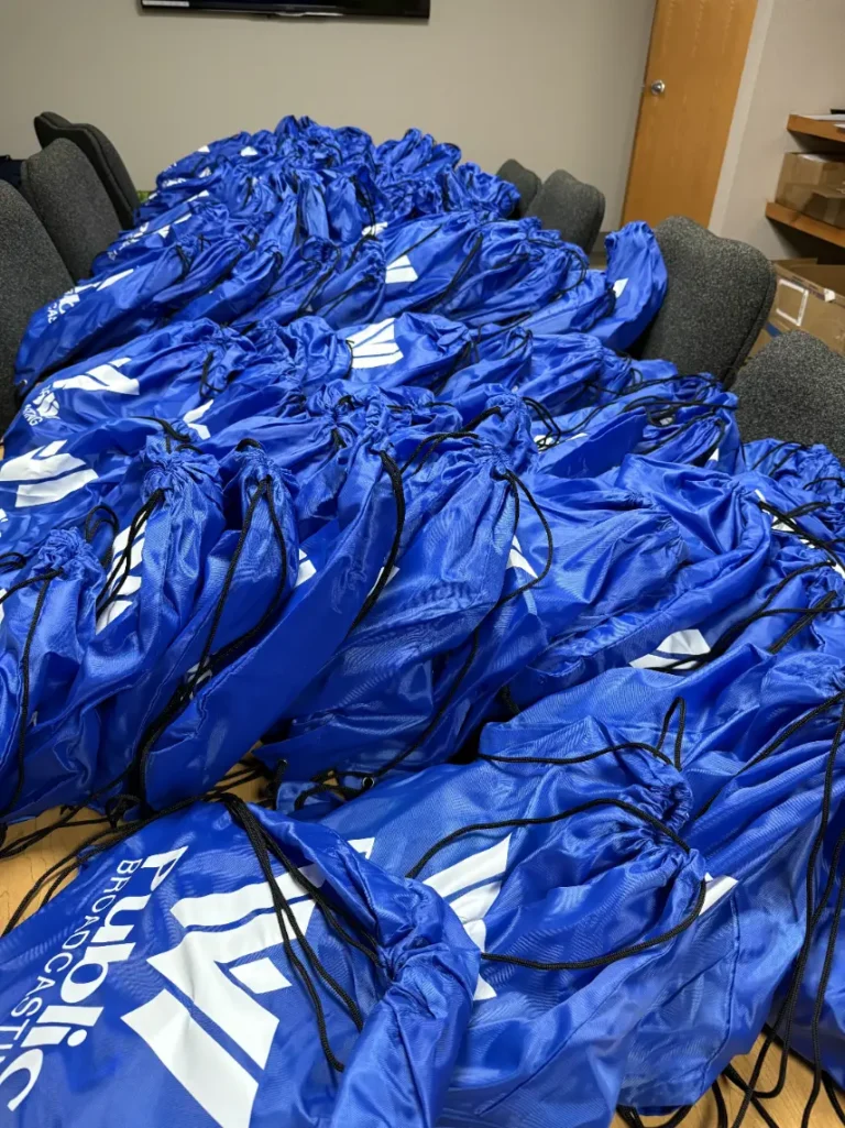 Dozens of blue bags full of goodies are shown on a table.