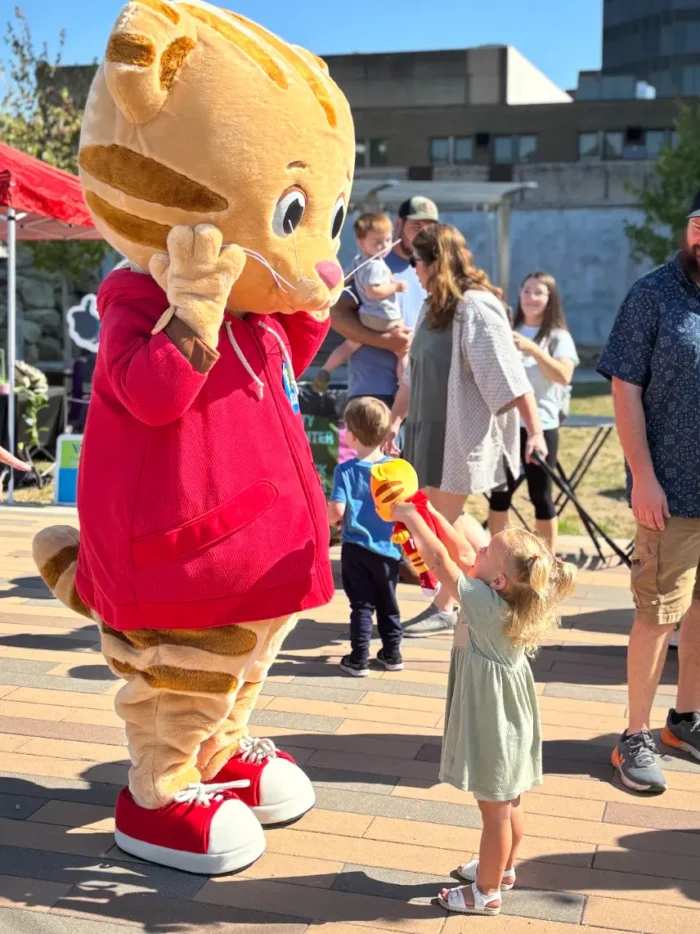 Daniel Tiger is shown a small Daniel Tiger stuffed toy by a little girl.