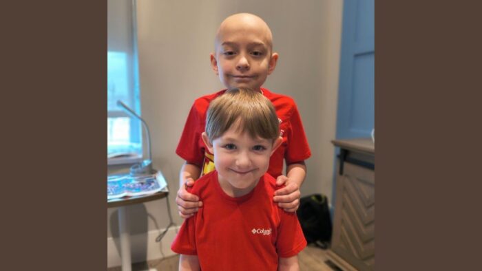 Two boys wearing red shirts posing for a photo.
