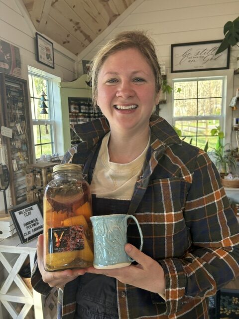 A white woman holding a blue mug and a jar.