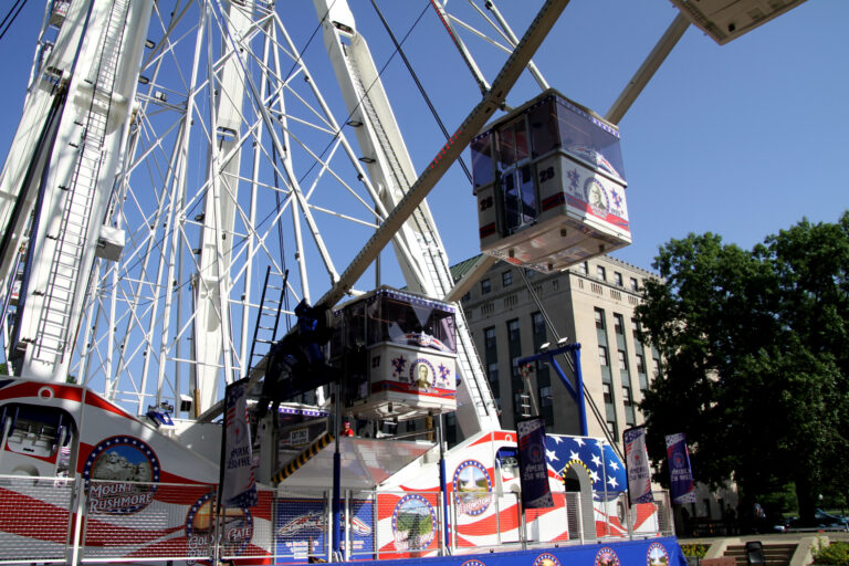 Cubes painted in blue and red hang from a Ferris wheel.