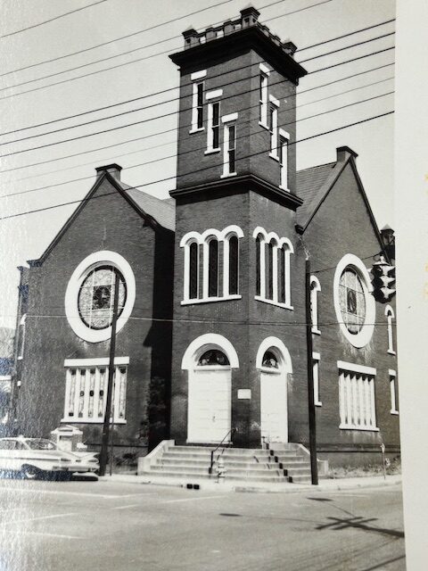 A black-and-white portrait of a church. There are two shorter sides of the building and a taller structure in the middle.