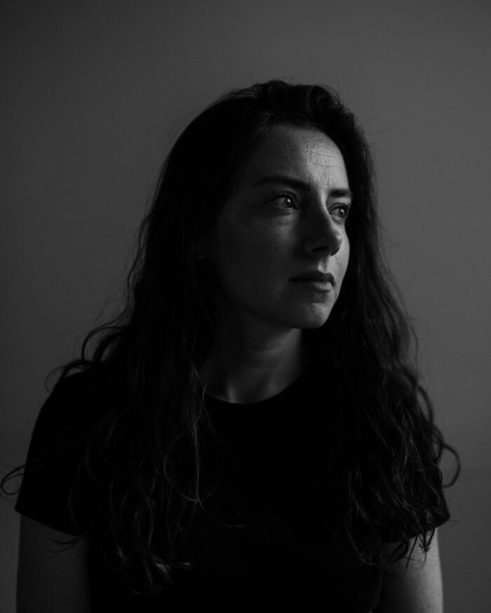 A black-and-white portrait photo of a woman. She is wearing a black shirt and looking off into the distance.