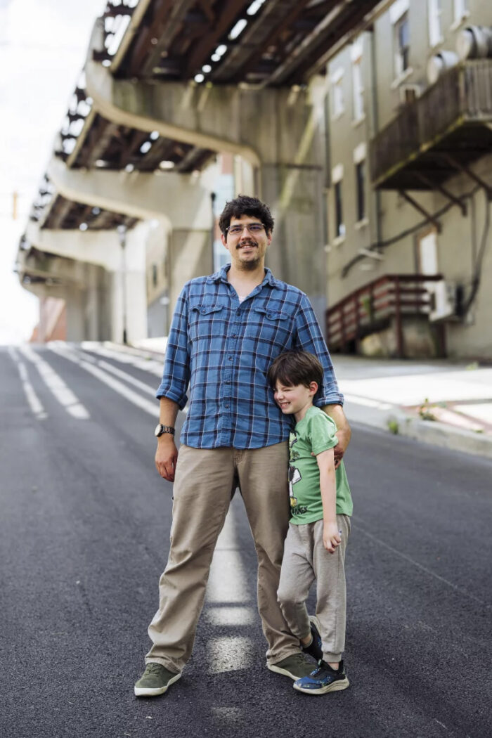 Man in blue plaid shirt and young boy standing in a street