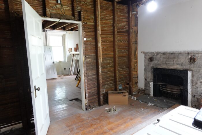 Photo shows the interior of an old wooden home, with walls removed down to the studs.