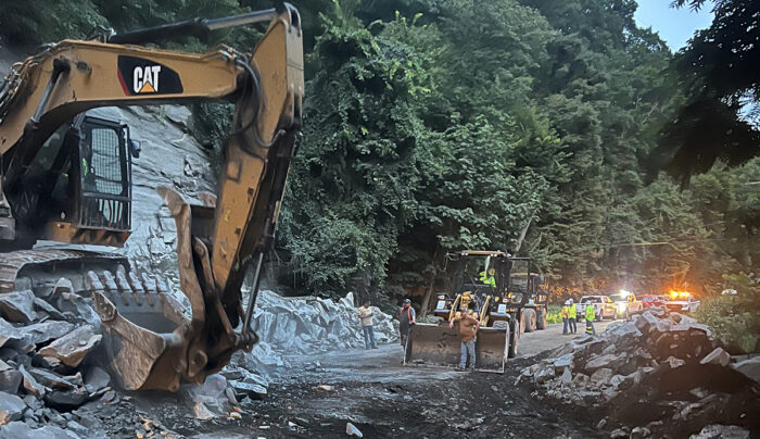 Heavy equipment breaks up rocks on a road