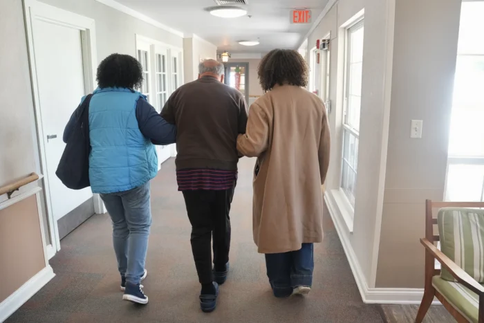 A landscape photo of three people walking down a hallway.