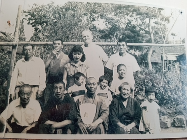 A black-and-white landscape portait of a Japanese family. There are 13 people in the photo. 