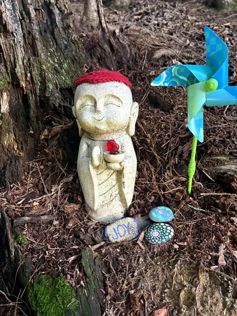 A tiny white statue of a child. It's wearing a red hat and holding a red trinket. 