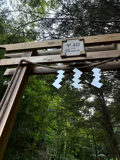 A gate with the Japanese word for "Peace." There are three jagged white ornaments hanging below the sign.