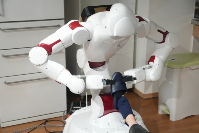 A white robot putting a show on someone's foot. 