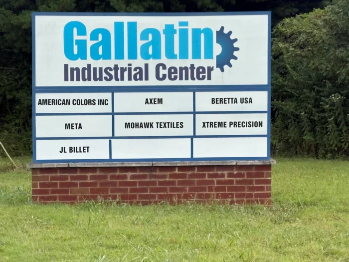 A sign outside that reads Gallatin Industrial Center. Several smaller signs on the larger sign read, American Colors Inc, Axem, Beretta USA, META, Mohawk Textiles, Xtreme Precision, and JL Billet.
