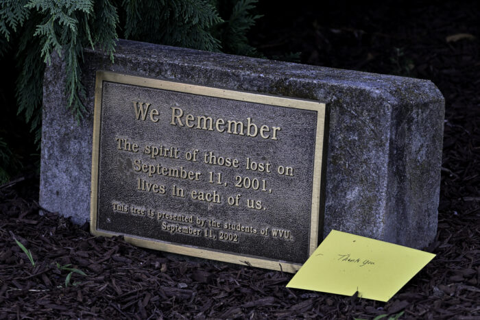 A bronze plaque on a stone backing includes the word "We Remember"