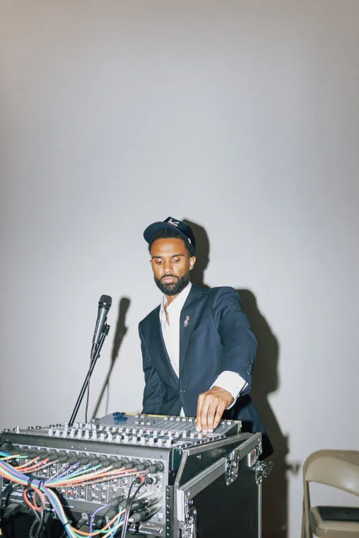 A portrait photo of a Black man mixing on a DJ board.