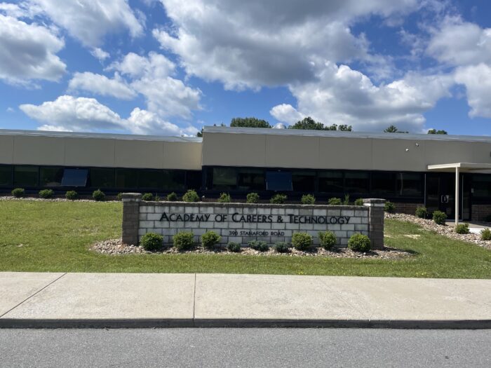 The front of a building outside on a cloudy day. A sign out front reads, Academy of Careers and Technology.