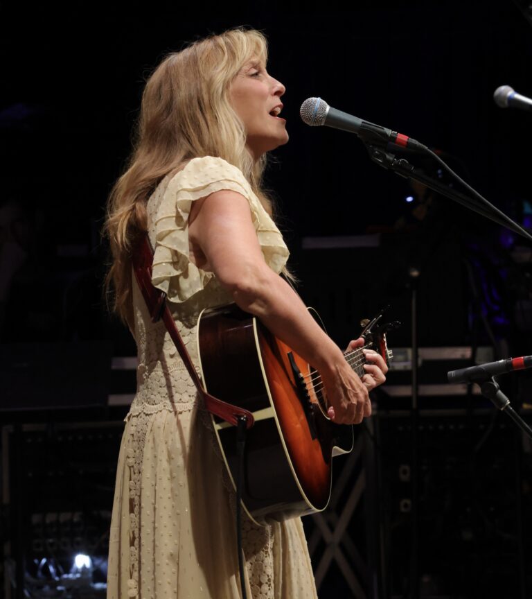 woman in white dress plays guitar