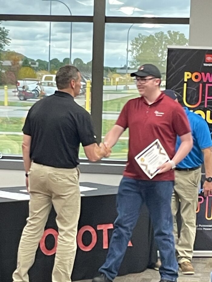 Two men shake hands at an event.