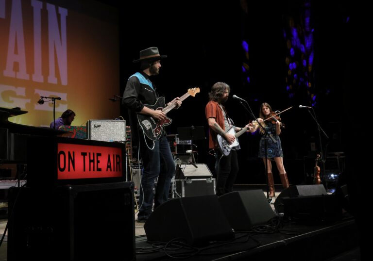 three musicians perform on a stage