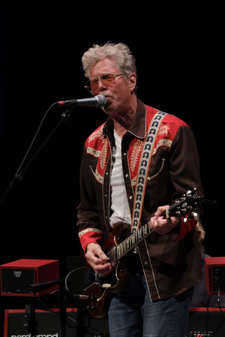 Man playing guitar sings into mic