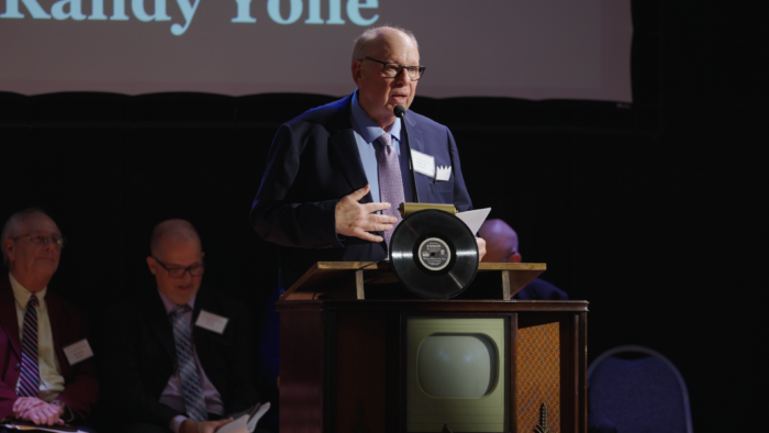 Bald man standing at a podium