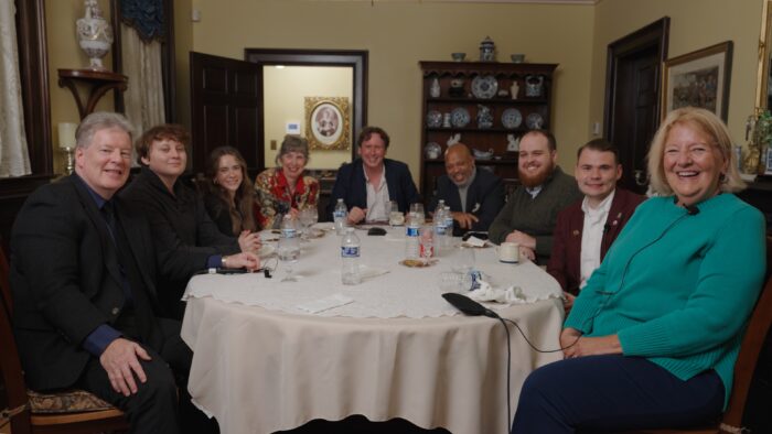 Nine people sit around a dinner table.