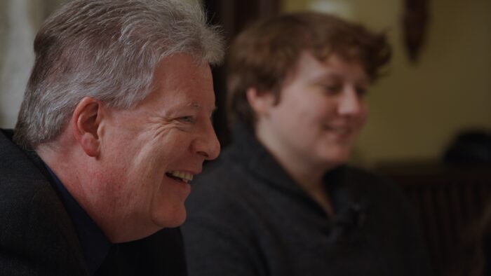 An older man and a young woman sitting at a dinner table.